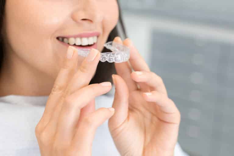 woman holding Invisalign clear teeth aligners
