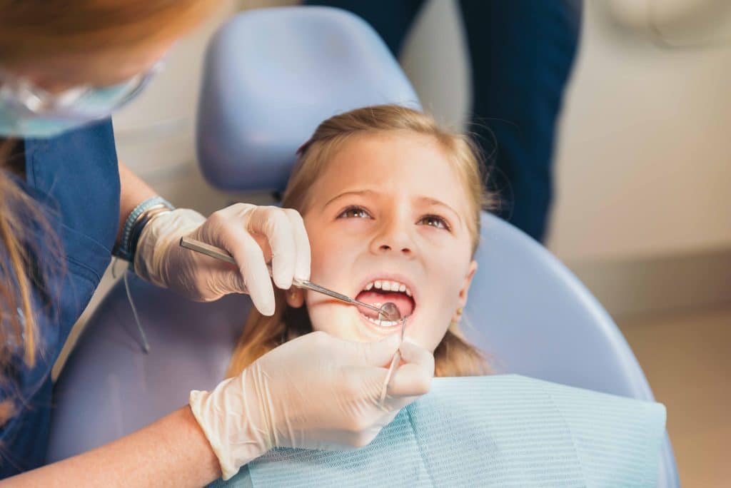 a girl with a dentist getting her teeth worked on